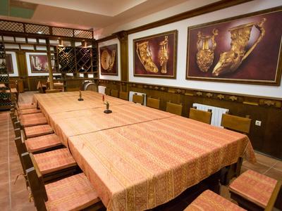 Lungo tavolo da conferenza con sedie in una stanza con scaffali per vino e quadri alle pareti.