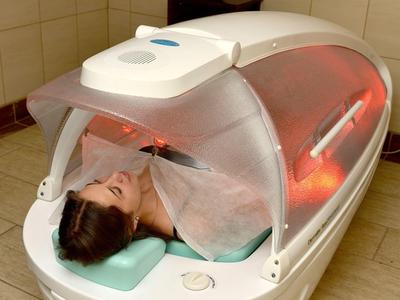 Donna rilassata in una moderna capsula benessere con luce rossa in una stanza spa.