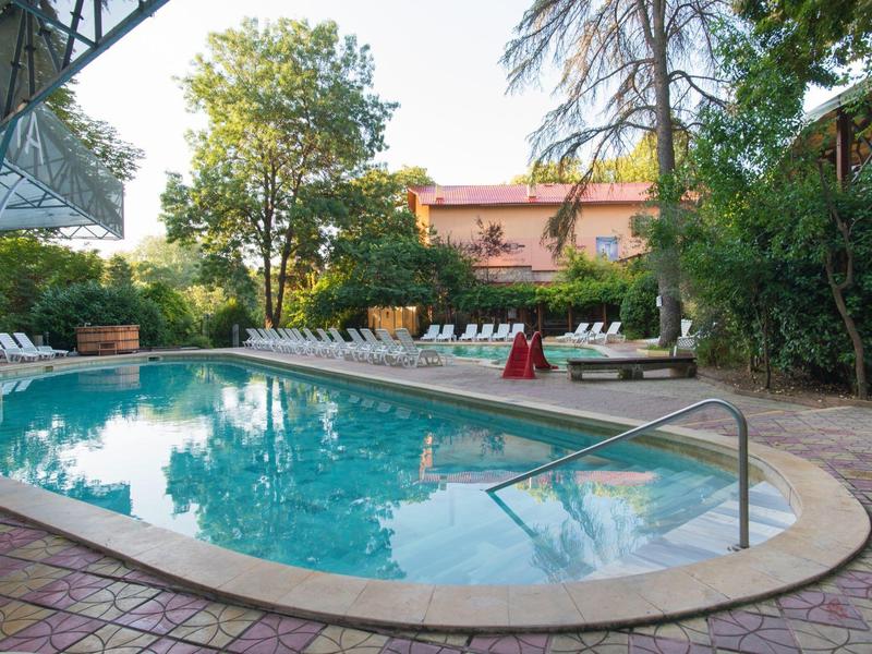 Piscina rotonda con lettini e vegetazione intorno in un giardino dell'hotel.