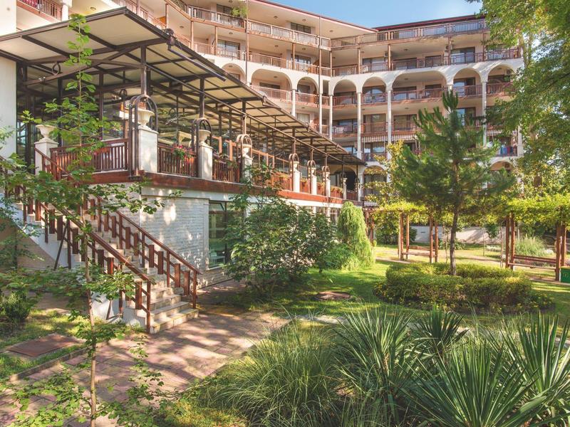 Grande edificio dell'hotel con balconi e giardino curato in primo piano