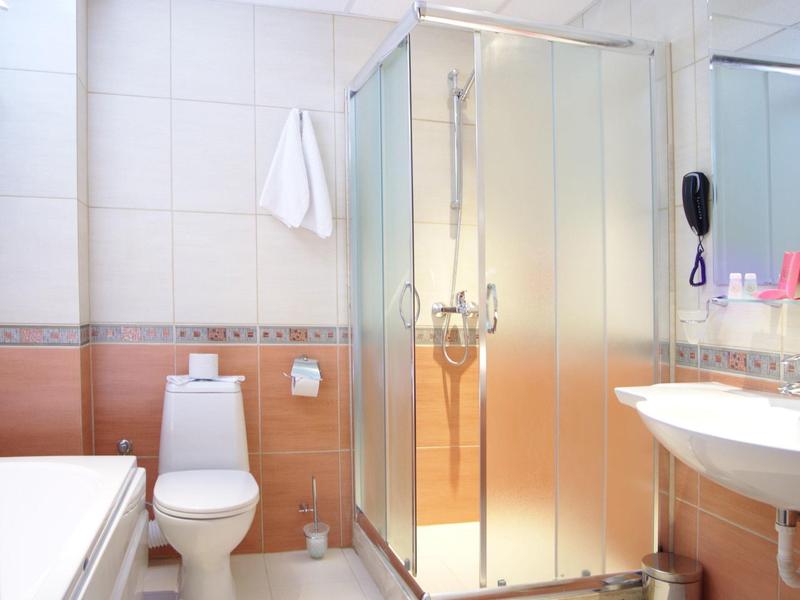 Bagno luminoso con doccia, toilette, lavabo e vasca da bagno in una camera d'hotel.