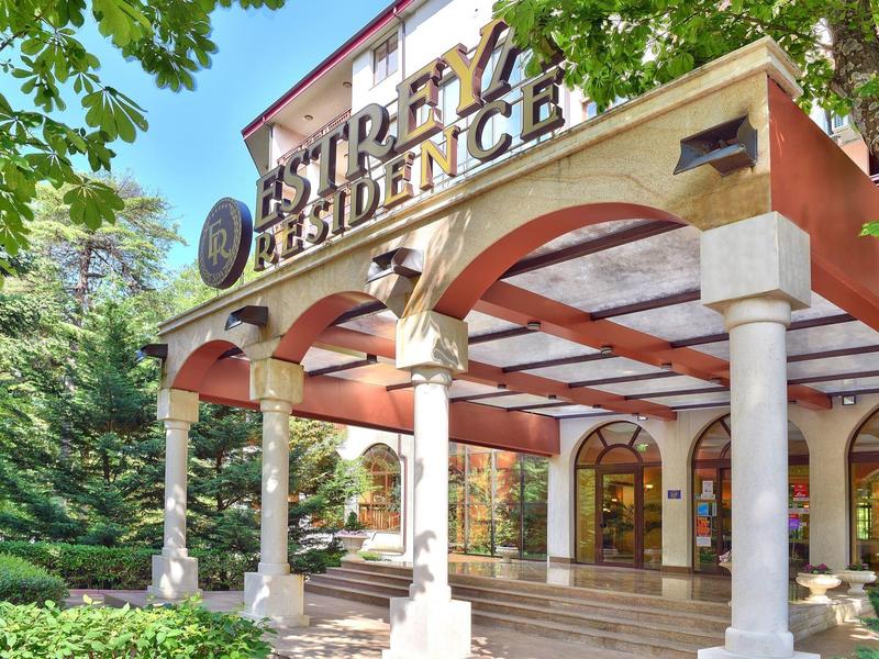 Edificio storico con colonne all'ingresso di un hotel o residenza circondato dal verde.