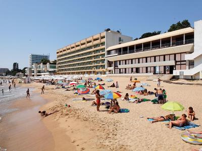 Spiaggia con bagnanti e grandi edifici di hotel sullo sfondo sotto un cielo sereno.