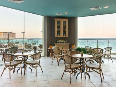 Terrazza aperta con sedie e tavoli con vista sul mare al tramonto.