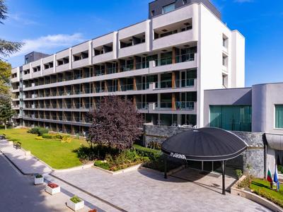 Edificio moderno di un hotel con balconi, alberi verdi e cielo limpido sullo sfondo.