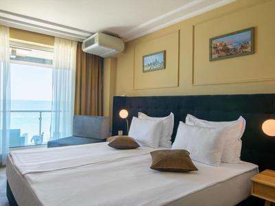 Camera d'hotel moderna con due letti singoli, balcone con vista mare e arredamento minimalista.