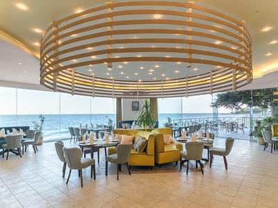 Ristorante moderno con vista sul mare, area salotto rotonda gialla e grande lampada a soffitto.