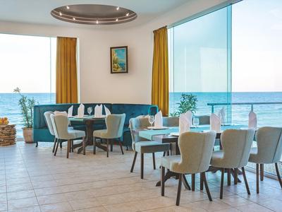 Zona pranzo moderna con vista mare attraverso una grande parete di vetro in una stanza luminosa.