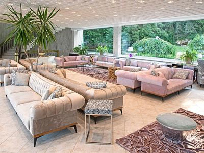 Soggiorno luminoso con più divani, grandi finestre e vista sul giardino.