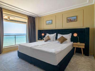 Modern eingerichtetes Hotelzimmer mit Meerblick durch großes Fenster.