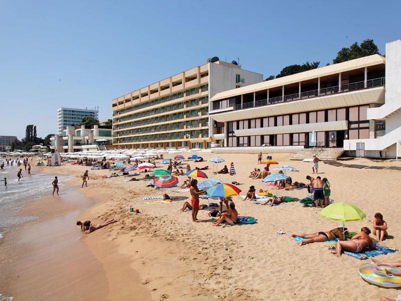 Spiaggia con bagnanti e grandi edifici di hotel sullo sfondo sotto un cielo sereno.