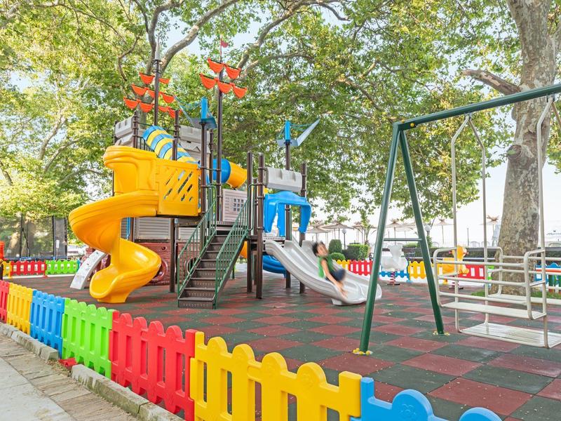 Parco giochi colorato per bambini con scivolo, altalene e recinto in plastica colorata.