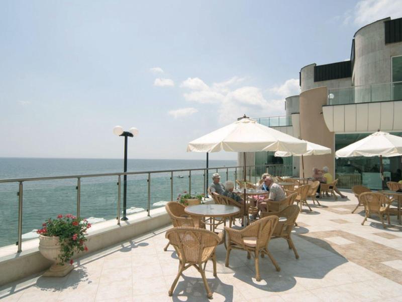 Terrazza con tavoli, sedie e ombrelloni con vista sul mare in una giornata di sole.