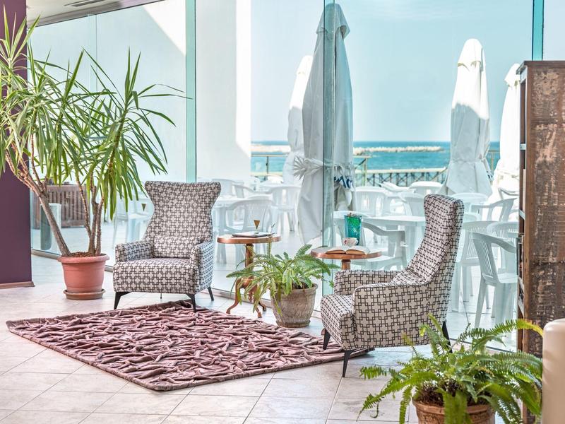 Accogliente zona salotto con due poltrone, tappeto e piante su un balcone con vista mare.