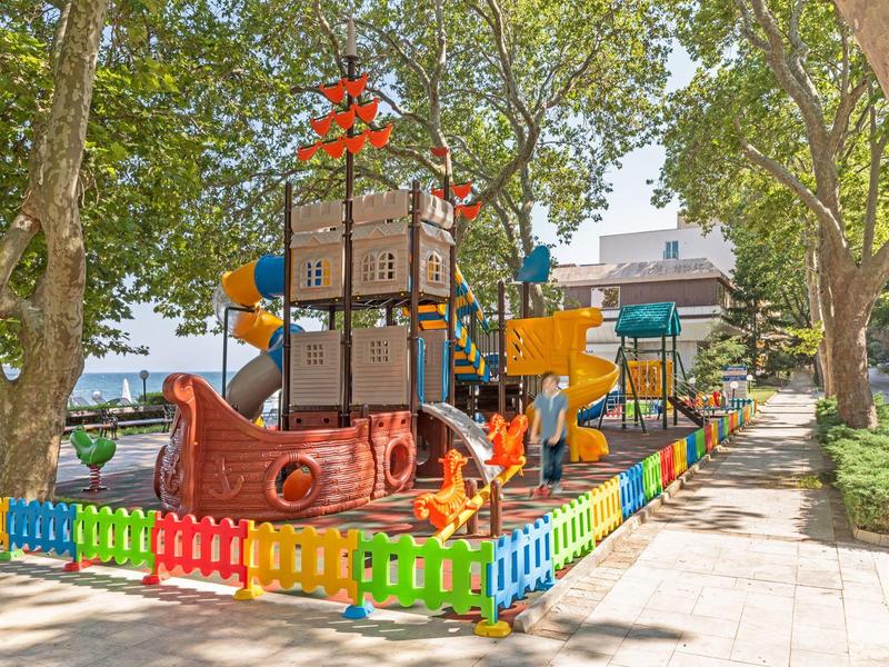 Area giochi colorata a tema nave pirata all'aperto accanto ad alberi e edifici