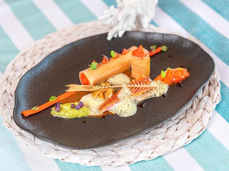 Piatto elegantemente impiattato con verdure e salsa su un piatto nero.