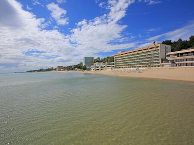 Strand met hotels langs de kust onder een blauwe lucht met enkele wolken.