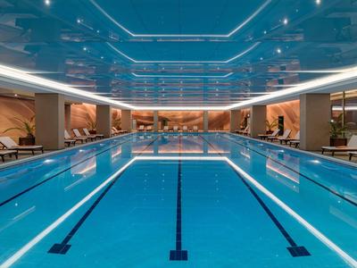 Interior of a modern indoor pool with blue lanes and comfortable lounge chairs.