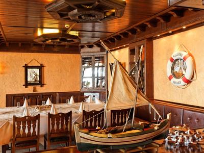 Cozy restaurant area with wooden furniture, nautical decor, and model sailboat