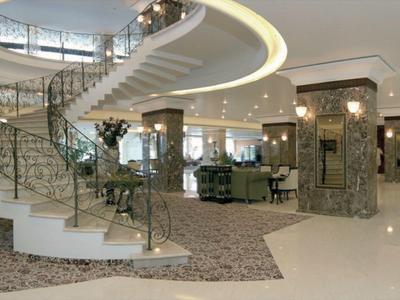 Spacious, elegant hotel lobby with curved staircase and marble cladding.