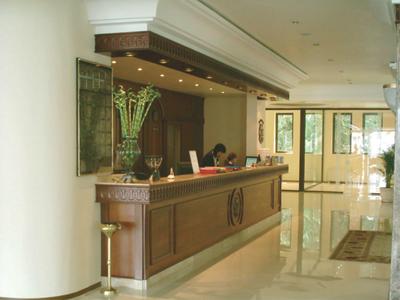 Elegant hotel lobby reception with wooden counter and glass vase filled with flowers.