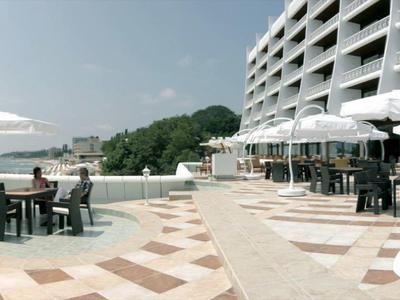 Modern hotel outdoor area with pool, sun loungers, and sea view.