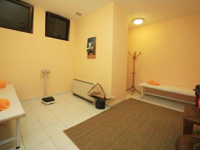 Cozy, simple massage or relaxation room with two beds, light walls, and ceiling light.