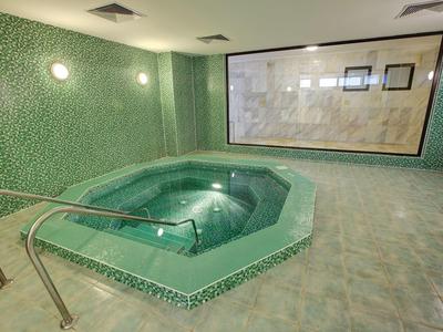 Modern heated hot tub in an elegant spa area with green patterned tiles.