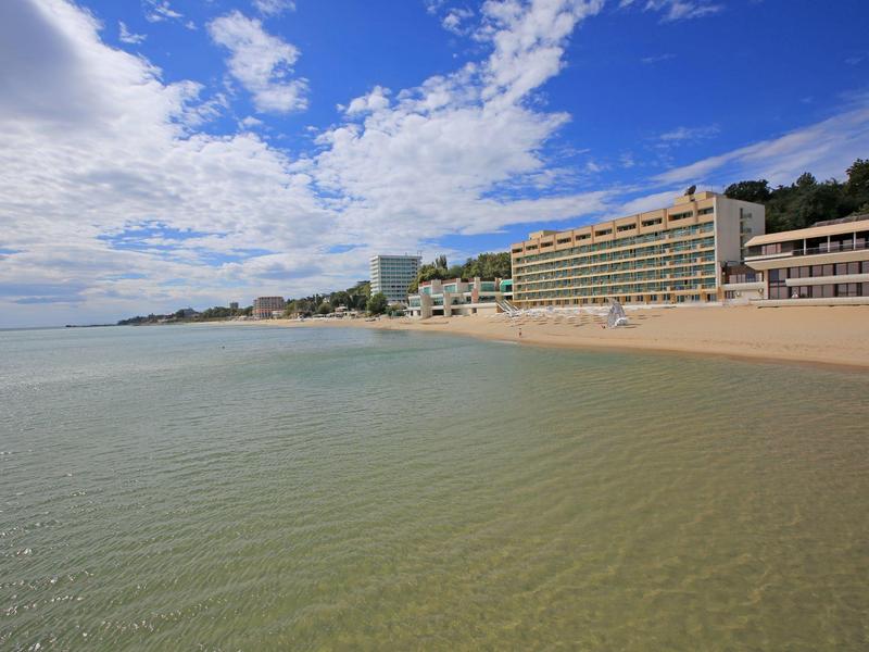Beach and hotel buildings along the coast under a blue sky with clouds