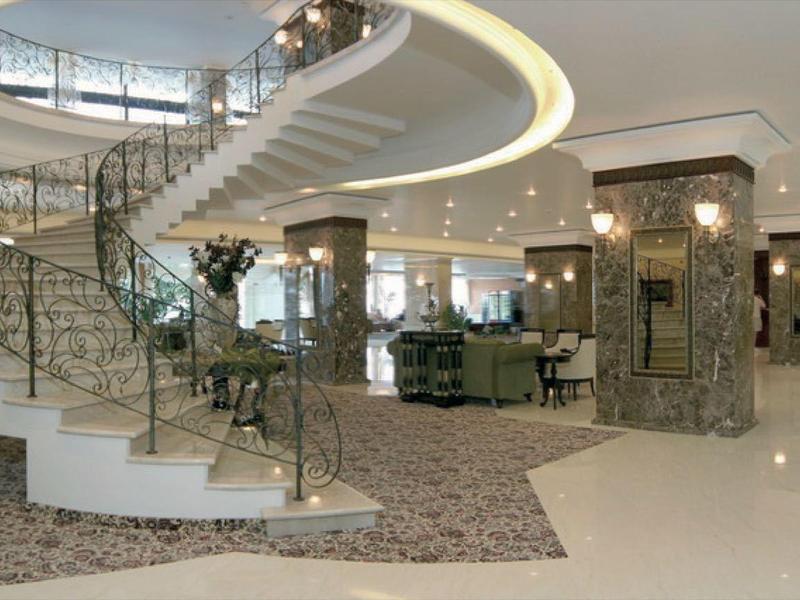 Spacious, elegant hotel lobby with curved staircase and marble cladding.