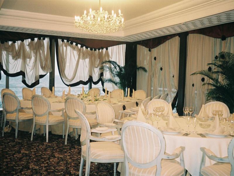 Elegant dining room with oval tables, white chairs, and chandeliers in a hotel.