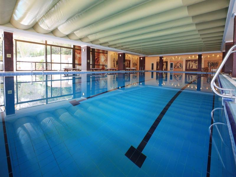 Indoor hotel swimming pool with blue water and large windows