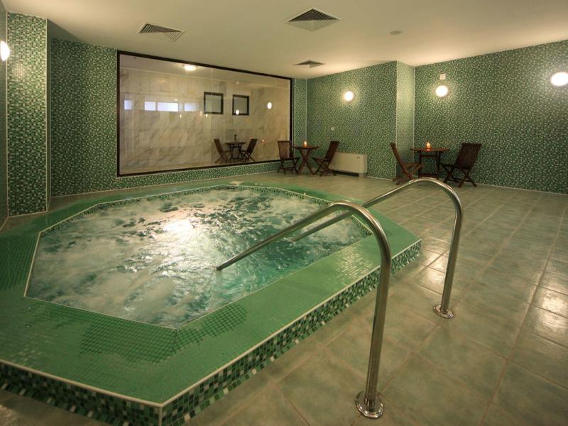 Indoor jacuzzi with green tiled basin and subdued lighting