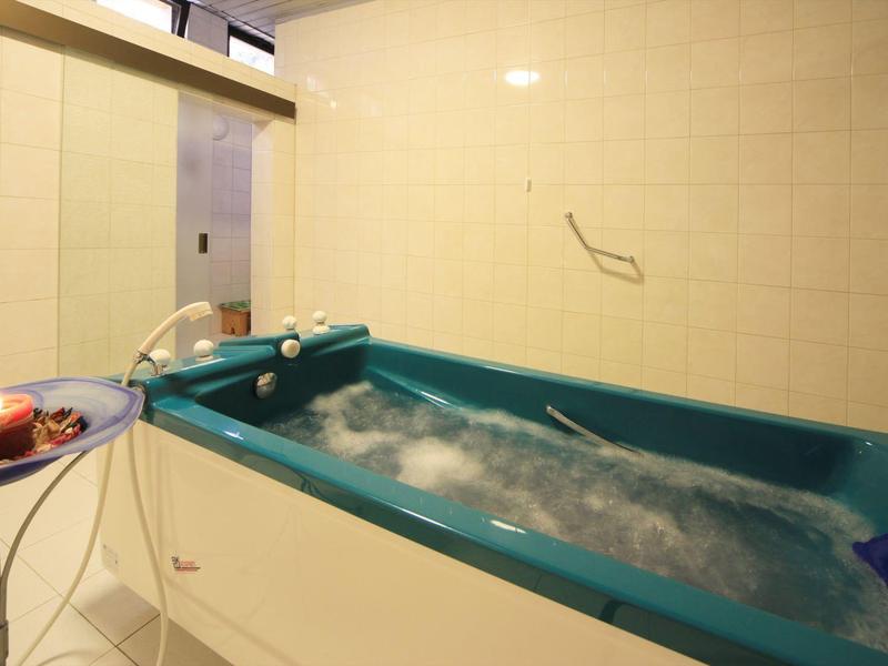 Modern whirlpool in a bright room with tiled walls and a snack table nearby.