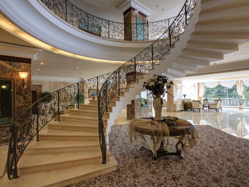 Elegant spiral staircase with ornate railing in a luxurious hotel lobby area.