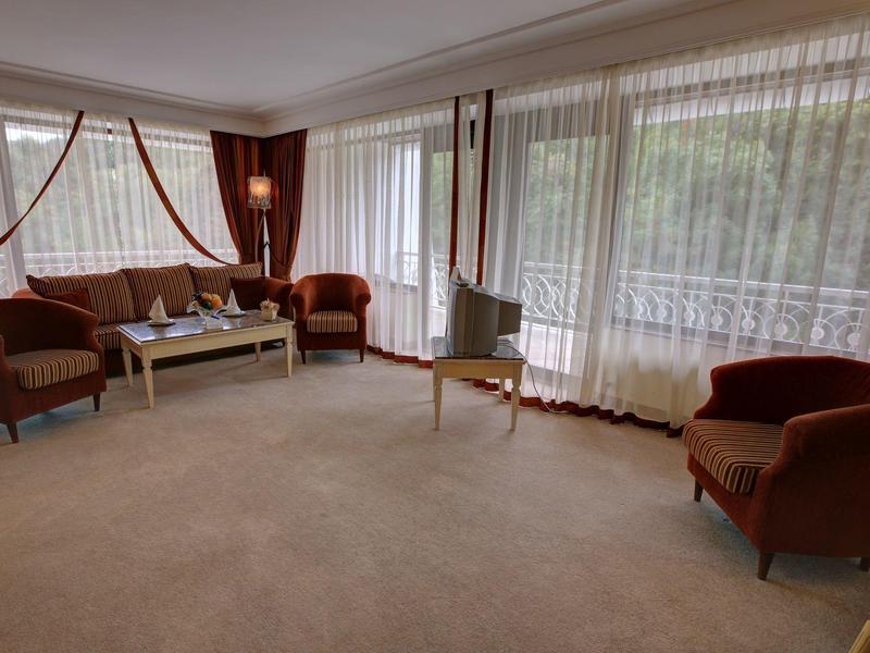 Bright living room with brown armchairs, white table, and large windows with curtains.