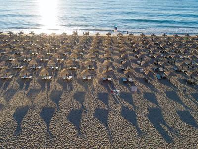 Strand met rijen parasols die lange schaduwen werpen bij zonsondergang