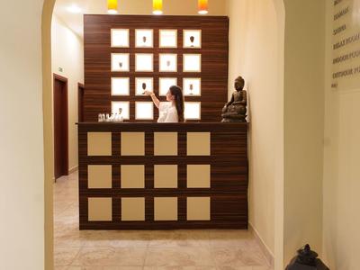 Espace de réception lumineux avec comptoir sombre, étagères murales décoratives et statue.