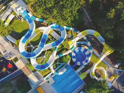 Luchtfoto van een kronkelende glijbaan in een waterpark omgeven door groen.