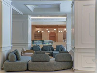 Area lounge d'hotel moderna con sedute grigie e pannelli murali bianchi.
