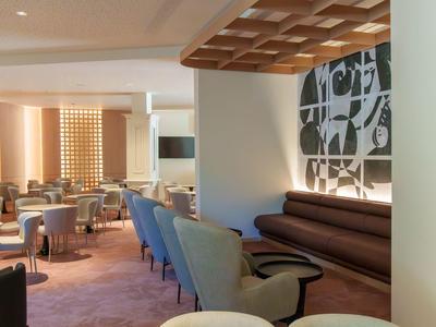 Area lounge di un hotel moderno con poltrone comode, elementi in legno e parete decorativa.