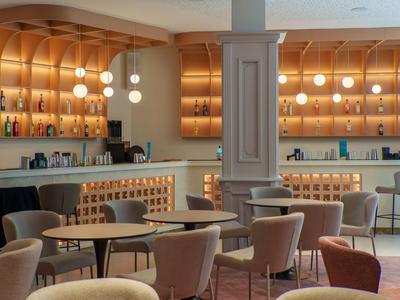 Area bar hotel moderna con eleganti scaffali in legno, sedute confortevoli e illuminazione calda