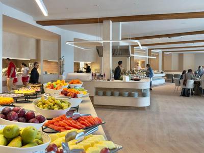 Un buffet con frutta fresca e ospiti in un ristorante d'hotel moderno.