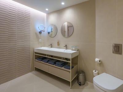 Modern bathroom with double sinks, round mirrors, and textured wall.