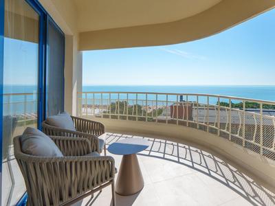 Balcony with two wicker chairs and small table overlooking the sea.