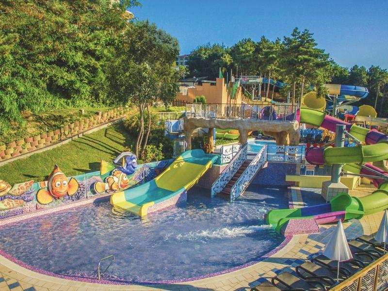 Parc aquatique coloré avec plusieurs toboggans et une grande piscine extérieure.