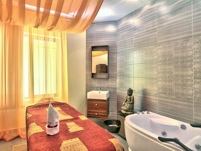 Chambre de bien-être moderne avec table de massage, baignoire et ambiance détendue.