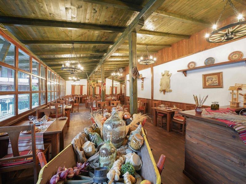 Restaurant rustique avec tables en bois, chaises et décorations traditionnelles aux murs.