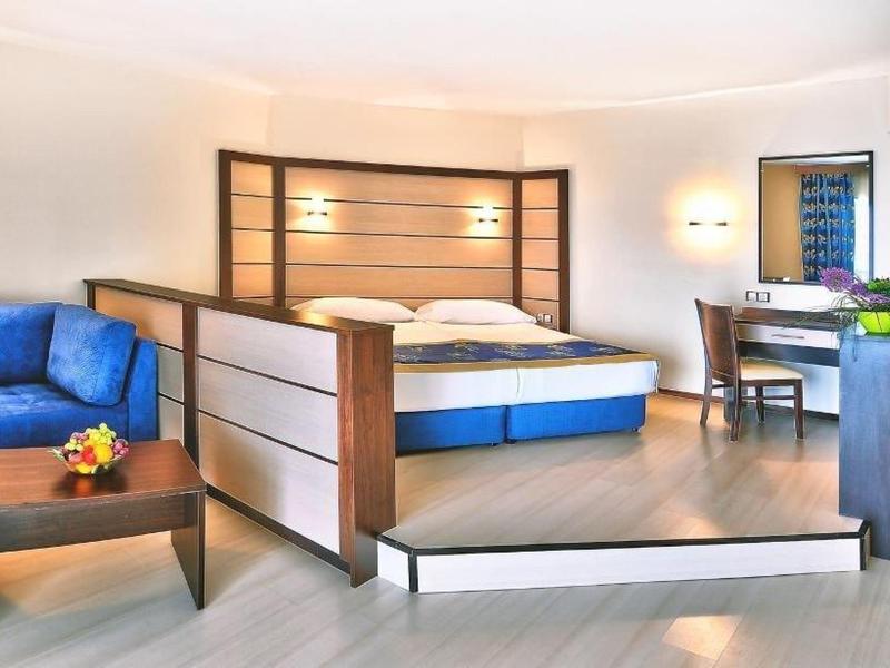 Chambre d'hôtel moderne avec lit, canapé bleu et bureau.