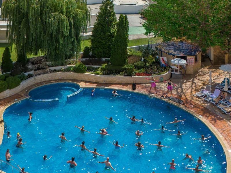 Piscine d'hôtel animée avec de nombreux nageurs et la mer en arrière-plan